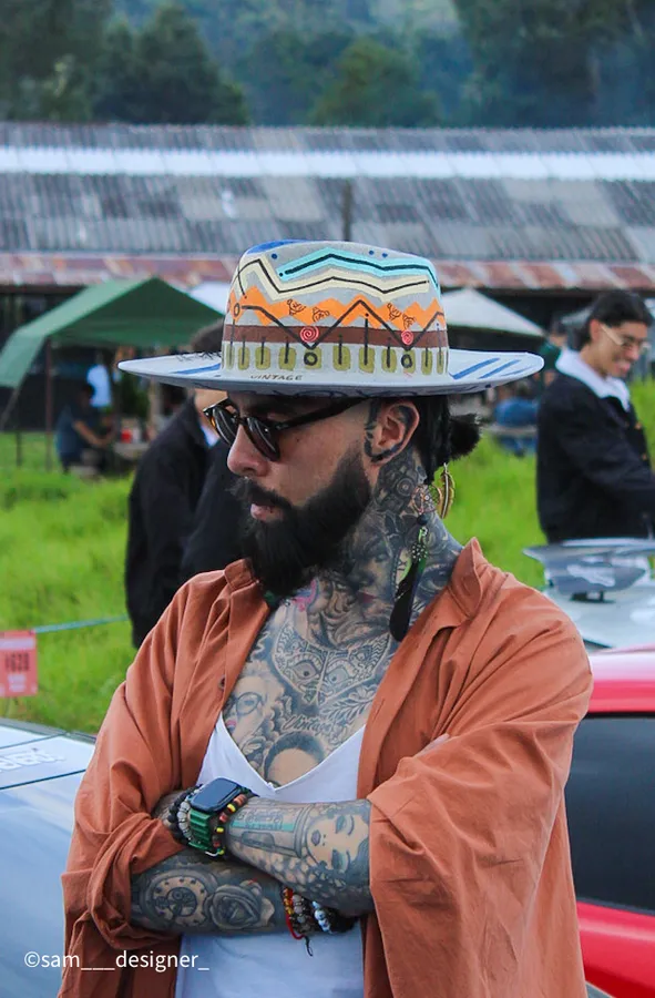 Retrato de un hombre con sombrero artesanal y tatuajes